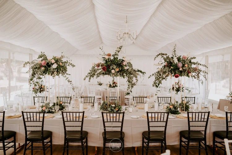 The Grand Marquee set for dinner with chandeliers, tall floral centrepieces and black chairs